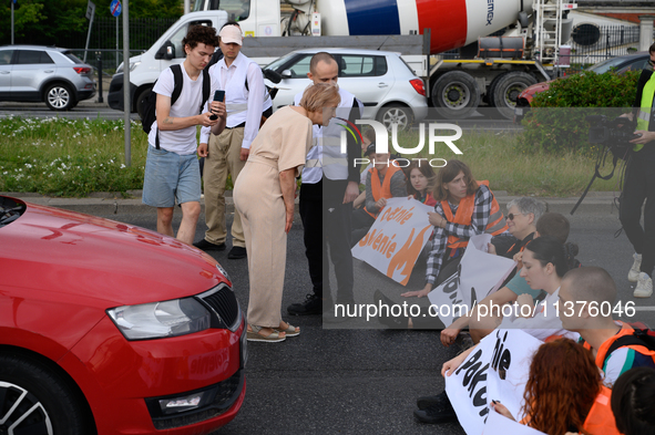 A woman is arguing with climate activists from the Last Generation (Ostatnia Generacja) as they are blocking a main road to protest against...