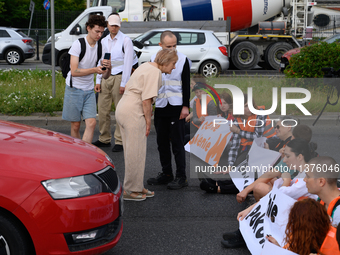 A woman is arguing with climate activists from the Last Generation (Ostatnia Generacja) as they are blocking a main road to protest against...