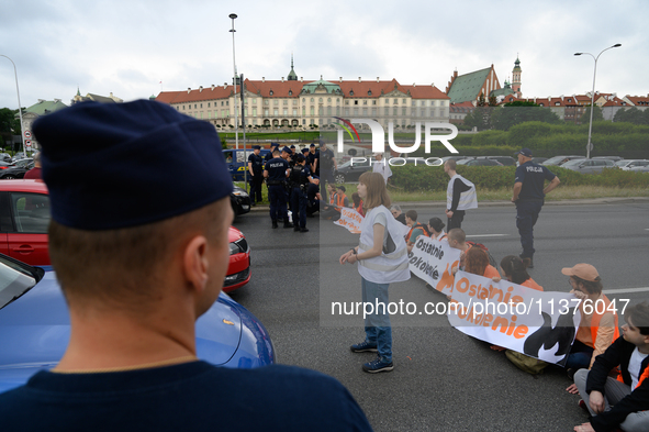 Police officers are talking to climate activists from the Last Generation (Ostatnia Generacja) as they are blocking a main road to protest a...