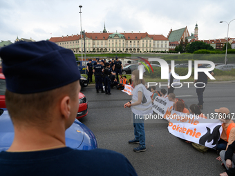 Police officers are talking to climate activists from the Last Generation (Ostatnia Generacja) as they are blocking a main road to protest a...