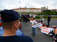 Police officers are talking to climate activists from the Last Generation (Ostatnia Generacja) as they are blocking a main road to protest a...