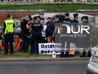 Police officers are detaining climate activists from the Last Generation (Ostatnia Generacja) as they are blocking a main road to protest ag...