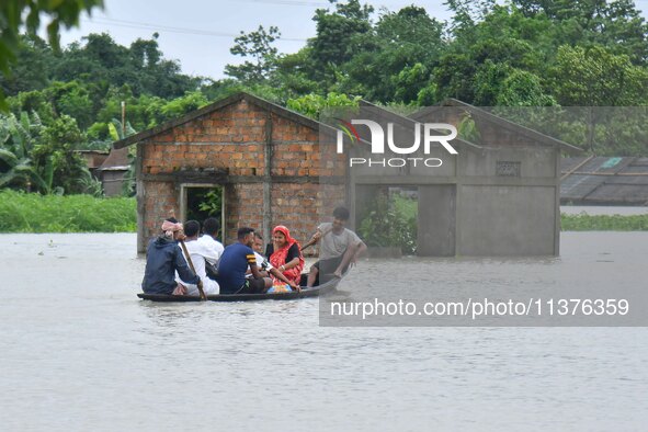 Villagers are paddling their boat near a submerged house in a village in Nagaon District of Assam, India, on July 1, 2024. 