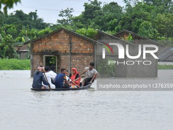 Villagers are paddling their boat near a submerged house in a village in Nagaon District of Assam, India, on July 1, 2024. (