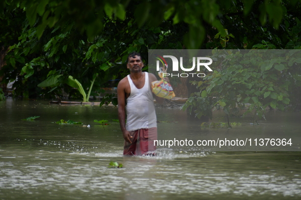 A man is walking through a flooded area in a village in Nagaon District of Assam, India, on July 1, 2024. 