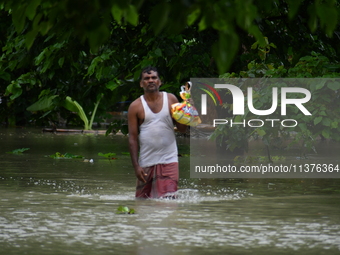 A man is walking through a flooded area in a village in Nagaon District of Assam, India, on July 1, 2024. (