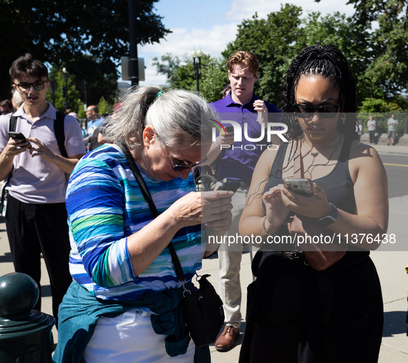 People outside the  U. S. Supreme Court check their phones for news of the Court's opinions on Donald Trump's immunity from prosecution for...