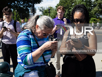 People outside the  U. S. Supreme Court check their phones for news of the Court's opinions on Donald Trump's immunity from prosecution for...