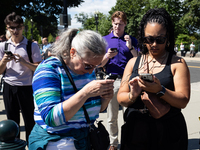 People outside the  U. S. Supreme Court check their phones for news of the Court's opinions on Donald Trump's immunity from prosecution for...