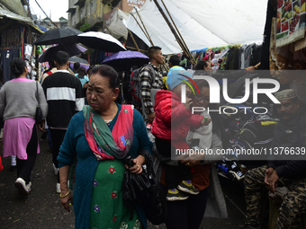 People are being seen in a market area during rainfall in Darjeeling, India, on July 1, 2024. Darjeeling is a famous tourist destination in...