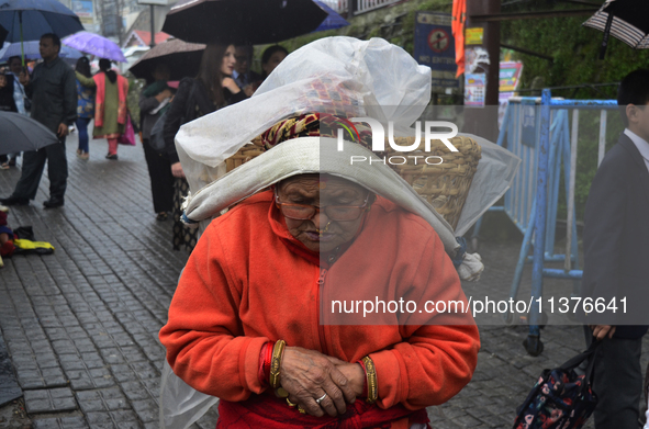 An old woman is carrying a heavy load during rainfall in Darjeeling, India, on July 1, 2024. Darjeeling is a famous tourist destination in N...