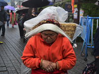 An old woman is carrying a heavy load during rainfall in Darjeeling, India, on July 1, 2024. Darjeeling is a famous tourist destination in N...