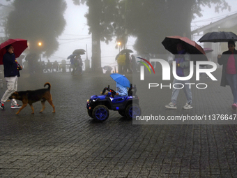 Pedestrians are carrying umbrellas during heavy rainfall in Darjeeling, India, on July 1, 2024. Darjeeling is a famous tourist destination i...