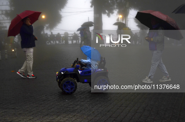 Pedestrians are carrying umbrellas during heavy rainfall in Darjeeling, India, on July 1, 2024. Darjeeling is a famous tourist destination i...