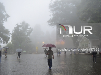 Pedestrians are carrying umbrellas during heavy rainfall in Darjeeling, India, on July 1, 2024. Darjeeling is a famous tourist destination i...