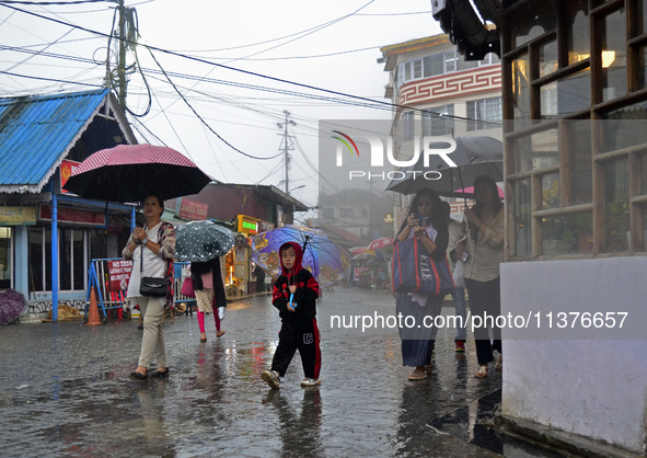 Pedestrians are carrying umbrellas during heavy rainfall in Darjeeling, India, on July 1, 2024. Darjeeling is a famous tourist destination i...