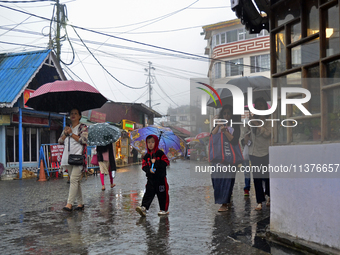 Pedestrians are carrying umbrellas during heavy rainfall in Darjeeling, India, on July 1, 2024. Darjeeling is a famous tourist destination i...