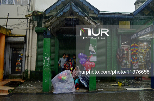 A toy seller is taking shelter during heavy rainfall in Darjeeling, India, on July 1, 2024. Darjeeling is a famous tourist destination in No...