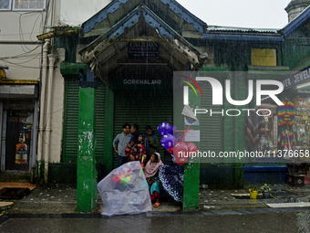 A toy seller is taking shelter during heavy rainfall in Darjeeling, India, on July 1, 2024. Darjeeling is a famous tourist destination in No...