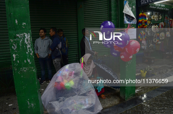 A toy seller is taking shelter during heavy rainfall in Darjeeling, India, on July 1, 2024. Darjeeling is a famous tourist destination in No...