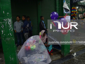 A toy seller is taking shelter during heavy rainfall in Darjeeling, India, on July 1, 2024. Darjeeling is a famous tourist destination in No...