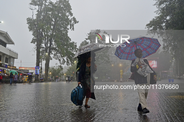 Pedestrians are carrying umbrellas during heavy rainfall in Darjeeling, India, on July 1, 2024. Darjeeling is a famous tourist destination i...