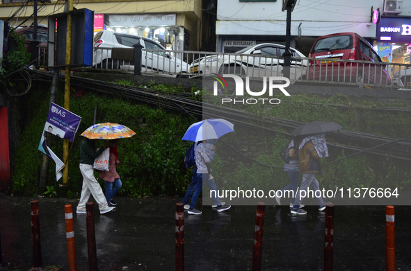 Pedestrians are carrying umbrellas during heavy rainfall in Darjeeling, India, on July 1, 2024. Darjeeling is a famous tourist destination i...