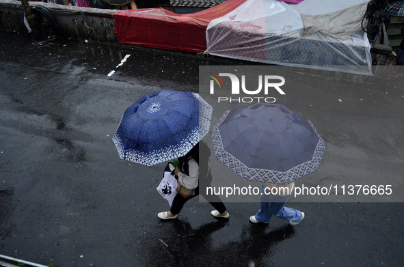 Pedestrians are carrying umbrellas during heavy rainfall in Darjeeling, India, on July 1, 2024. Darjeeling is a famous tourist destination i...