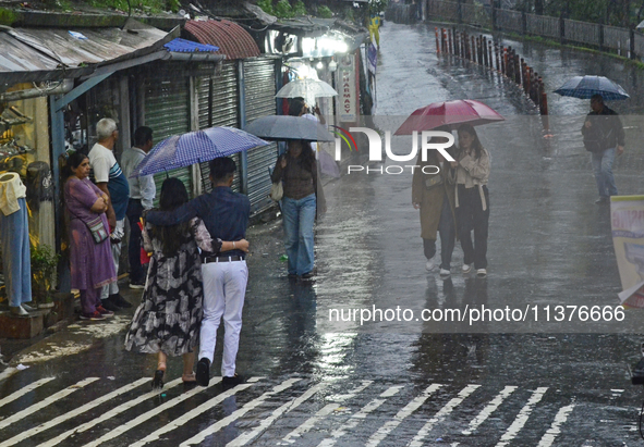 Pedestrians are carrying umbrellas during heavy rainfall in Darjeeling, India, on July 1, 2024. Darjeeling is a famous tourist destination i...