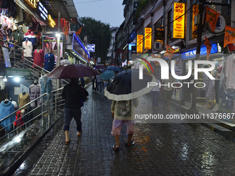 Pedestrians are carrying umbrellas during heavy rainfall in Darjeeling, India, on July 1, 2024. Darjeeling is a famous tourist destination i...