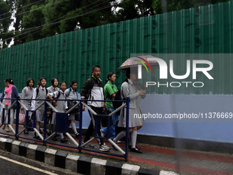 School students are carrying umbrellas during heavy rainfall in Darjeeling, India, on July 1, 2024. Darjeeling is a famous tourist destinati...