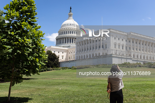 A woman takes a photo of the Capitol shortler after the U. S. Supreme Court issued the last remaining opinions of the term, including a deci...