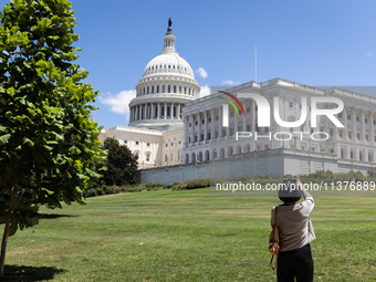 A woman takes a photo of the Capitol shortler after the U. S. Supreme Court issued the last remaining opinions of the term, including a deci...