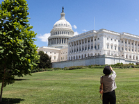 A woman takes a photo of the Capitol shortler after the U. S. Supreme Court issued the last remaining opinions of the term, including a deci...