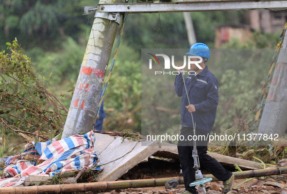 An electric worker is carrying out a repair operation at Si'an Village in Liuzhou, China, on July 2, 2024. 