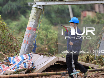 An electric worker is carrying out a repair operation at Si'an Village in Liuzhou, China, on July 2, 2024. (