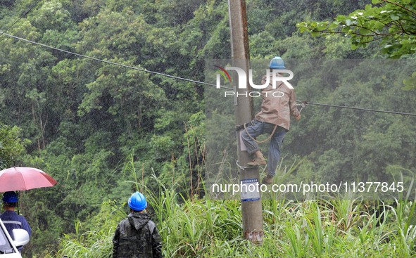 An electric worker is carrying out a repair operation at Si'an Village in Liuzhou, China, on July 2, 2024. 