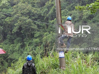 An electric worker is carrying out a repair operation at Si'an Village in Liuzhou, China, on July 2, 2024. (