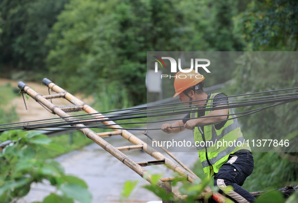 An electric worker is carrying out a repair operation at Si'an Village in Liuzhou, China, on July 2, 2024. 