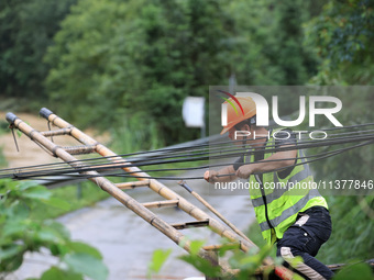 An electric worker is carrying out a repair operation at Si'an Village in Liuzhou, China, on July 2, 2024. (