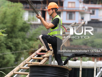 An electric worker is carrying out a repair operation at Si'an Village in Liuzhou, China, on July 2, 2024. (