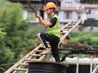 An electric worker is carrying out a repair operation at Si'an Village in Liuzhou, China, on July 2, 2024. (