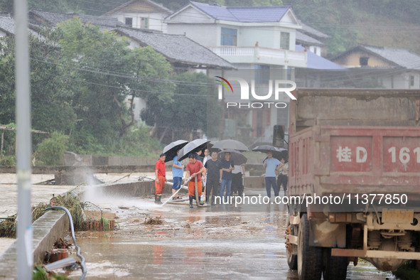 Workers are helping flood victims wash mud from a road at Si 'an village in Liuzhou, China, on July 2, 2024. 