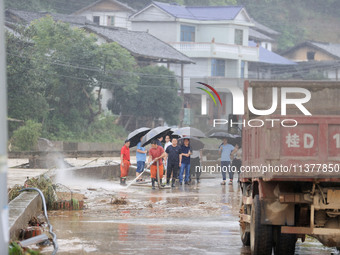 Workers are helping flood victims wash mud from a road at Si 'an village in Liuzhou, China, on July 2, 2024. (