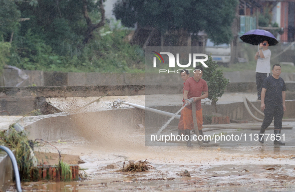 Workers are helping flood victims wash mud from a road at Si 'an village in Liuzhou, China, on July 2, 2024. 