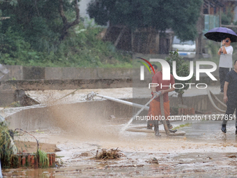 Workers are helping flood victims wash mud from a road at Si 'an village in Liuzhou, China, on July 2, 2024. (