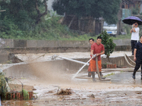 Workers are helping flood victims wash mud from a road at Si 'an village in Liuzhou, China, on July 2, 2024. (