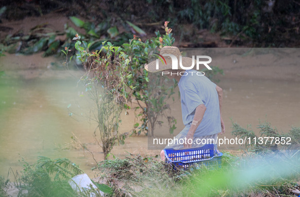 An elderly man is cleaning garbage from a farm at Si 'an Village in Liuzhou city, South China's Guangxi Zhuang Autonomous region, on July 2,...