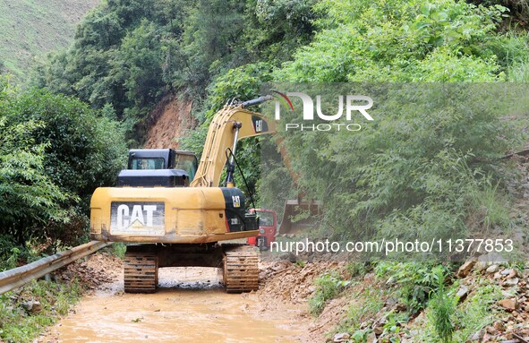 A rescue worker is driving an excavator to remove debris from a landslide at Si 'an village in Liuzhou, China, on July 2, 2024. 