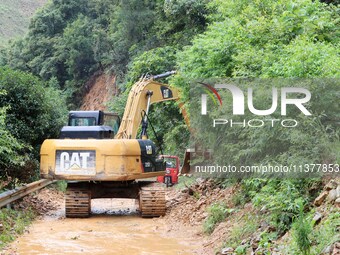 A rescue worker is driving an excavator to remove debris from a landslide at Si 'an village in Liuzhou, China, on July 2, 2024. (